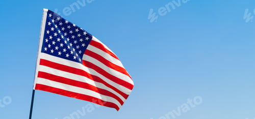Preview: American flag waving in the wind against blue sky