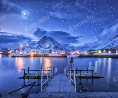 Preview: Fishing boats near pier on the sea and snowy mountains at night