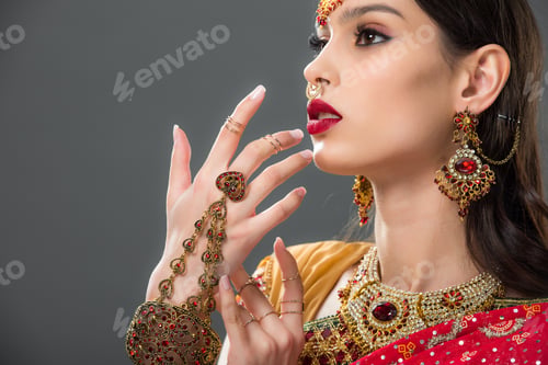 Preview: indian woman in traditional sari and accessories gesturing isolated on grey