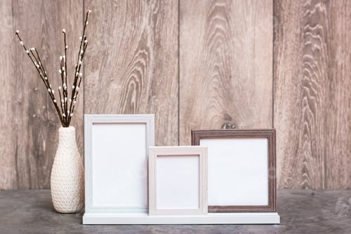 Preview: Three empty photo frames on the stand and a vase with artificial willow branches are on the table.
