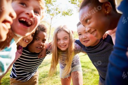 Preview: Group of smiling schoolchildren lean in to camera embracing