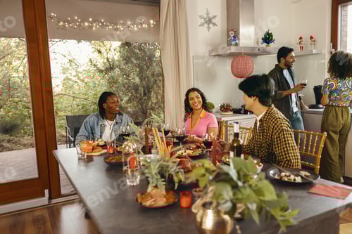 Preview: Happy friends enjoying in conversation and drinking wine during festive dinner at home party