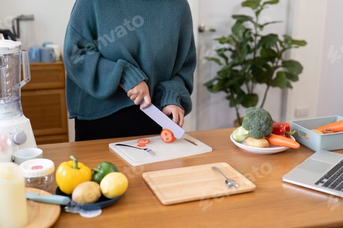 Preview: Woman slicing veggies on a cutting board in the kitchen