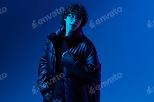Preview: Man in winter down jacket model posing with glasses, hipster lifestyle, portrait blue background