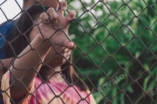 Preview: Kid's hands on a metal chain link wire mesh fence.