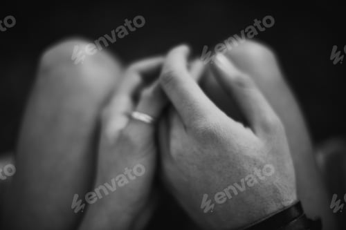 Preview: Finding love in dark places. Top view black and white image of two lovers holding hands.