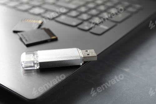 Preview: Usb flash drive, SD memory cards and laptop on grey textured table, closeup