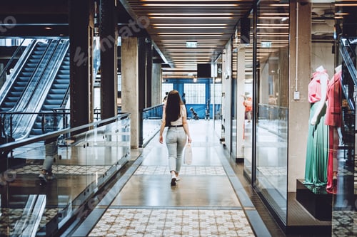 Preview: Modern Latina young woman walking in large modern mall. Young pretty brunette female consumer