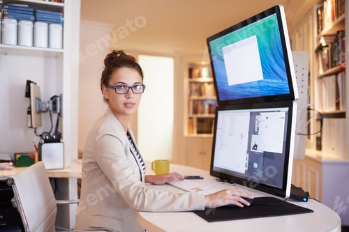 Preview: Portrait of a young woman working on a dual-screen computer at home