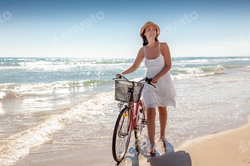 Preview: Woman Walking with Bicycle on Sandy Beach Shoreline