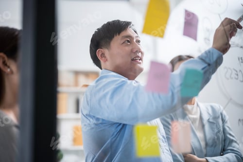 Preview: Asian business team meeting, collaborating and sharing ideas with colorful notes on a glass wall.