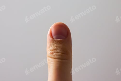 Preview: Closeup of a human thumb under the lights against a white background