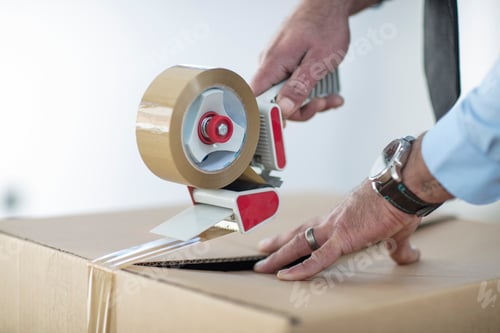 Preview: Hands sealing a cardboard box with tape dispenser