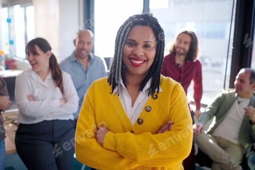 Preview: Confident businesswoman smiling with crossed arms in office with colleagues