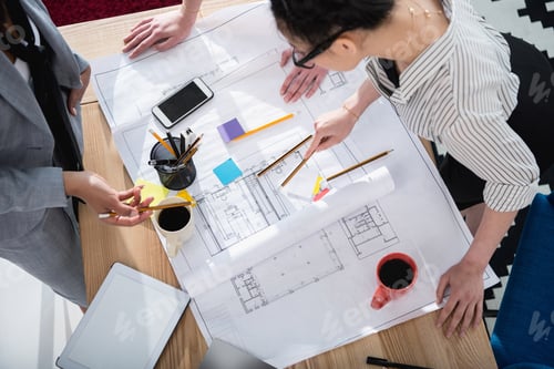 Preview: Cropped shot of professional young architects working with blueprint
