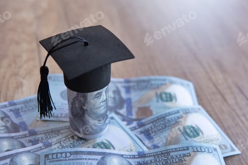 Preview: Closeup image of graduation cap and money on table.