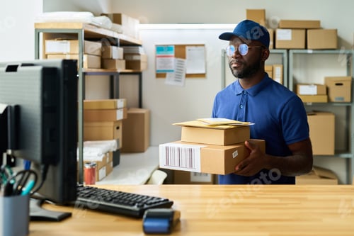 Preview: Young Adult Black Man Wearing Cap Holding Packages While Working in Warehouse