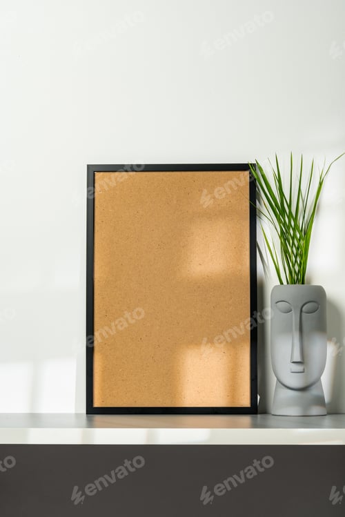 Preview: Black wooden frame and gray vase with plant leaves against white wall