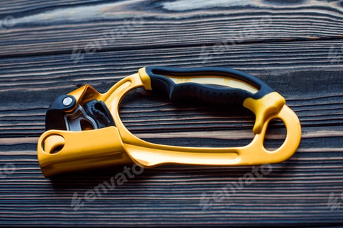 Preview: Isolated photo of climbing equipment. Part of carabiner lying on the wooden table