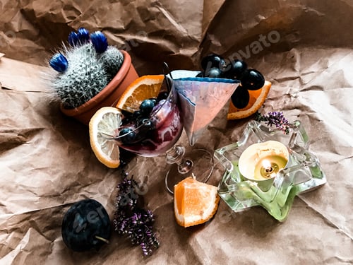 Preview: Blackberry alcohol drink with ice cube in glass surrounded with fruits and cactus on the background