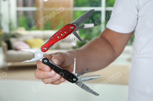 Preview: Man holding compact portable multitool indoors, closeup