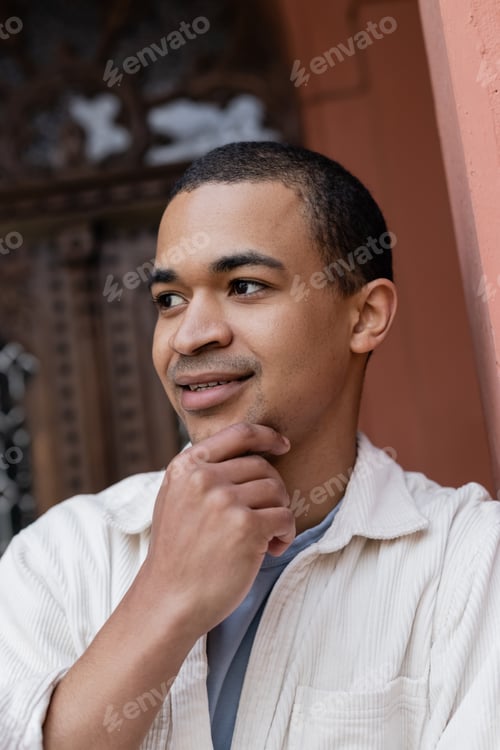 Preview: thoughtful african american man in shirt jacket near building in europe