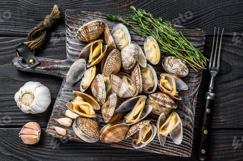 Preview: Shells Clams vongole on a wooden cutting board. Black wooden background. Top view