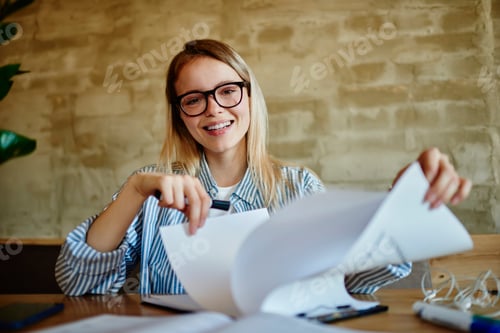 Preview: Happy female in glasses working with papers on clipboard in cafeteria
