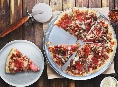 Preview: meaty pepperoni and sausage pizza sliced on metal tray in flat lay composition