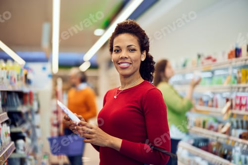 Preview: Portrait of a beautiful African female customer standing in a supermarket.