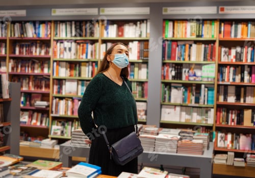 Preview: Young lady in face mask stands in bookstore during covid19 outbreak
