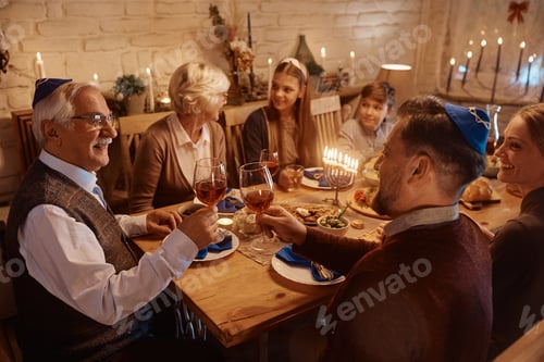 Preview: Happy Jewish men toasting with wine during family dinner on Hanukkah.