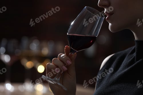 Preview: Woman with glass of red wine against blurred background, closeup. Space for text
