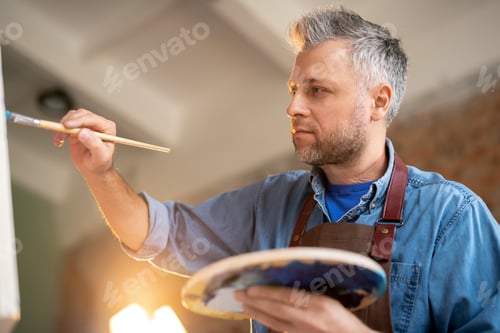 Preview: Contemporary artist with palette and paintbrush drawing details of painting