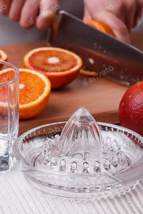 Preview: young woman in a gray apron cuts blood orange
