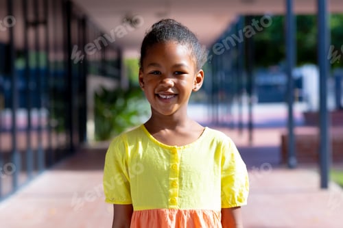Preview: Portrait of smiling biracial schoolgirl standing in sunny school yard with copy space