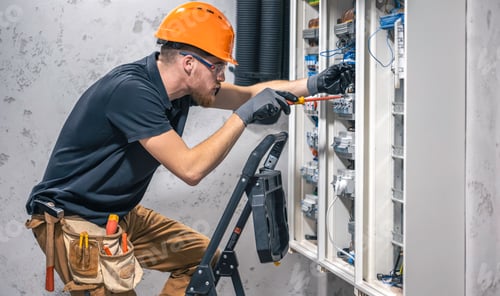 Preview: Young adult electrician civil engineer screwing equipment into fuse box.
