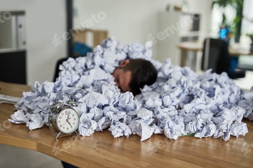 Preview: Shot of a young businessman surrounded by piles of paper in an office