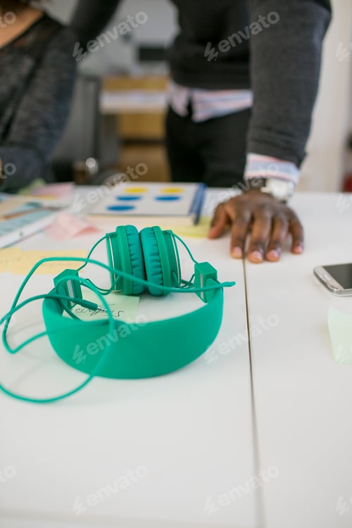 Preview: Close-up of headphones with business people in background