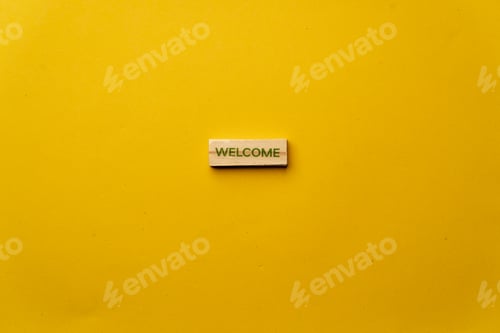 Preview: a yellow warm background without shadows wooden cubes with black letters laid out word welcome