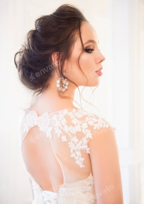 Preview: Beautiful brunette woman with bouquet posing in a wedding dress