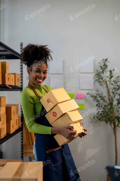 Preview: A woman is holding a stack of boxes and smiling