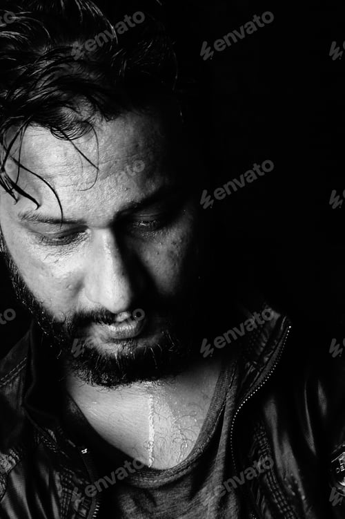 Preview: Attractive and sweaty bearded Indian man looking down in black and white
