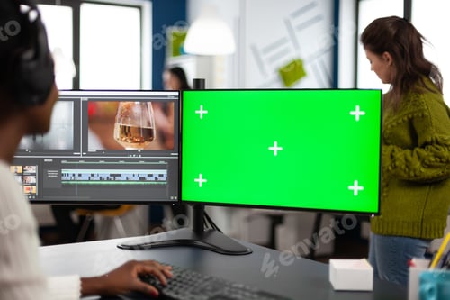 Preview: African video editor with headset editing footage using pc with greenscreen