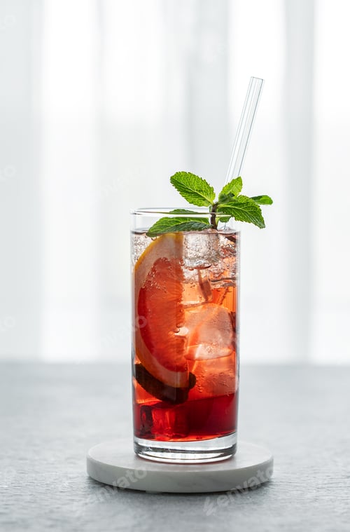 Preview: Lemonade with grapefruit, mint and ice on a marble stand on a table against a window