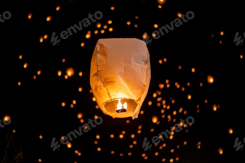 Preview: Lantern glowing brightly,rising against dark night sky,surrounded by smaller illuminated lanterns