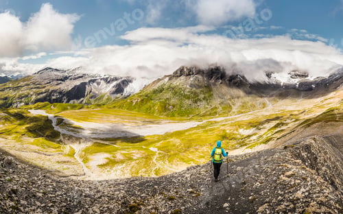 Preview: Solo hiker admiring the majestic mountain view on a sunny day