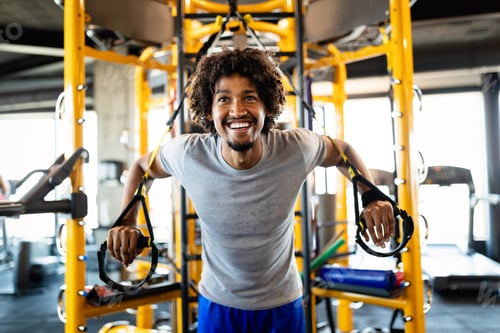 Preview: Handsome fit man having fitness TRX training at gym