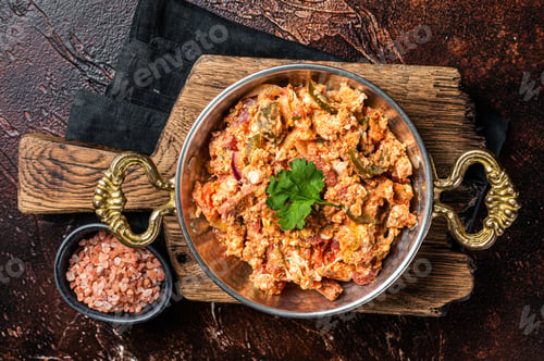 Preview: Turkish Menemen omelet with vegetabls and sucuk in askillet. Dark background. Top view