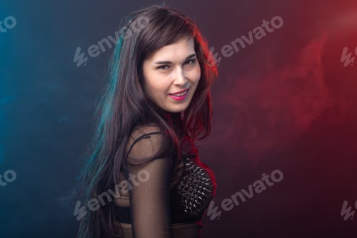Preview: Alluring young beautiful brunette woman in a provocative dress posing on a dark background. Concept
